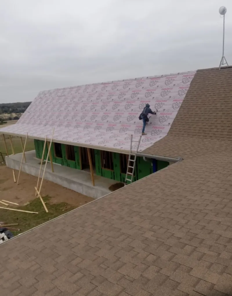 Worker preparing underlayment for a metal roof installation in Stillwater